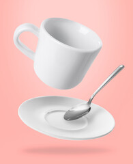 Spoon, cup and saucer falling on pink background