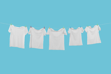 T-shirts drying on washing line against light blue background