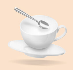 Spoon, cup and saucer falling on beige background