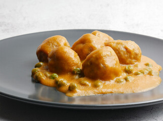Homemade plate of meatballs with tomato sauce and peas.