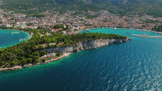Tranquil Seaside with Rustic Charm and Mountain Views. Calm beachfront, traditional boats in Makarska Riviera, Croatia.