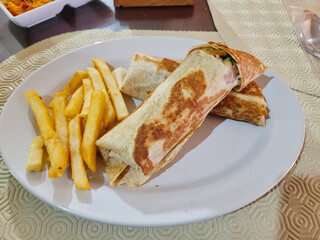 Grilled Wrap with French Fries on a White Plate