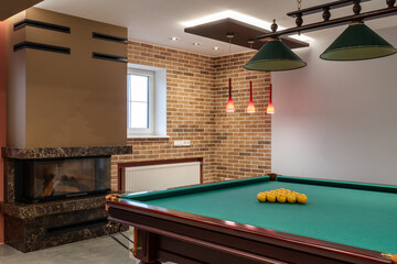 Billiard table with yellow balls in a room with a fireplace