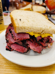 Delicious stacked pastrami sandwich on toasted rye, served on a white plate