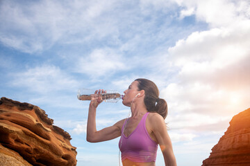 sporty woman drinking water from a bottle, thirsty after exercise.