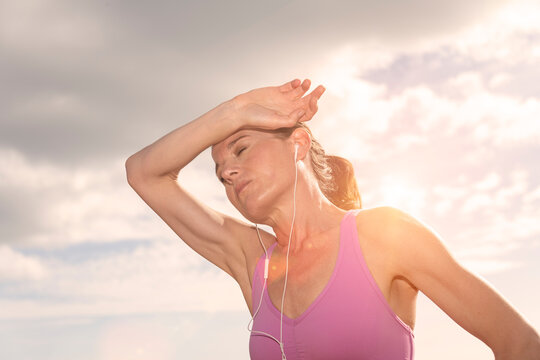 sporty woman hot after exercise in the sun,  hand to head