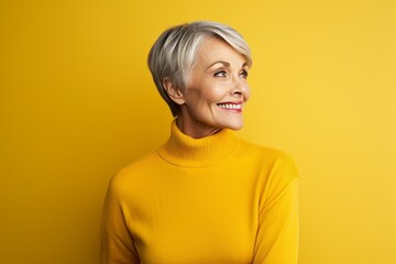 happy senior woman in yellow turtleneck looking up over yellow background