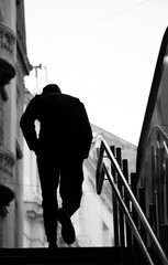 Blurry silhouette of a young man walking alone up the city subway stairs with hands in pockets - 738329233
