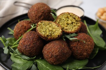 Delicious falafel balls and herbs on plate, closeup