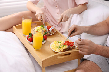 Obraz na płótnie Canvas Couple eating tasty breakfast on bed, closeup