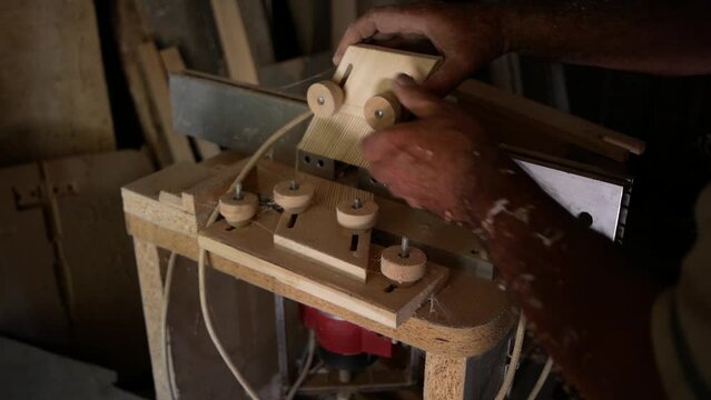 An old craftsman who works with metal and wood. The unusual kja machine is his invention for precisely holding and moving the piece of wood being processed