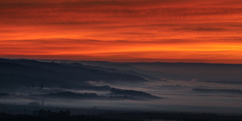 Fototapeta premium Nascer do sol vermelho sobre serra com nevoeiro