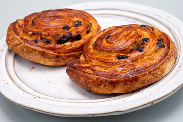 Breakfast in bakery with fresh baked coffee buns sweet pastry with raisins, morning food close up