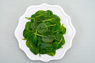 Fresh green baby Spinach leaves, diet and health concept, weight loss, spinach on ceramic plate, copy space