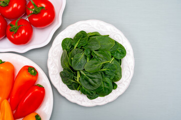 Fresh tomatoes, paprika, green Spinach leaves, diet and health concept, weight loss, spinach on ceramic plate, copy space