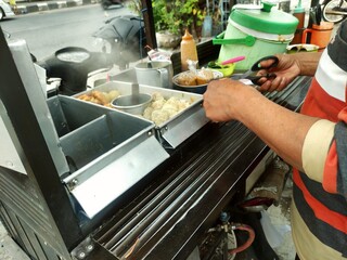 The seller preparing siomay to serve the customer. PKL or MSME concept. Siomay is Indonesian street...