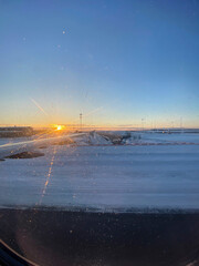 Sunset dusk shining on a snowy landing airport track seen from an airplane window