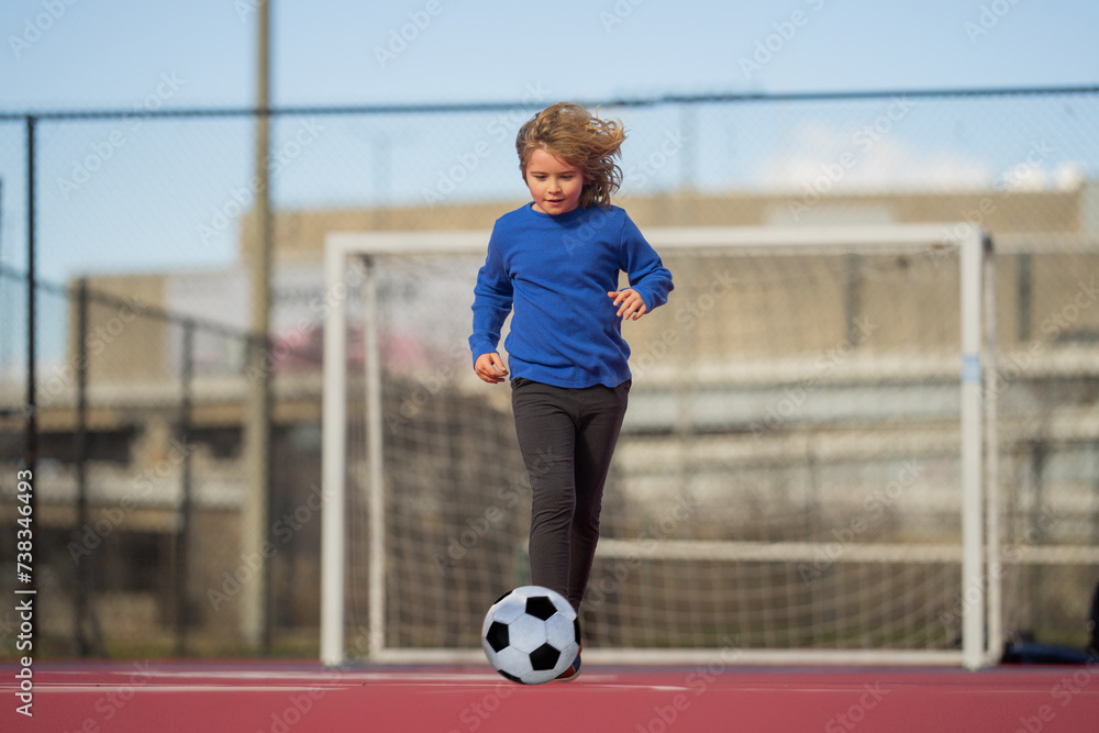 Wall mural Child boy hold classic soccer ball on playground. Kid holding football ball in studio. Kid playing with ball. Sport, soccer hobby for kids. Little football player posing with soccer ball.