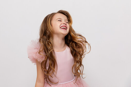 Portrait of emotional laughing little girl in pink dress over white background. Birthday celebration party concept. Holiday banner with copy space