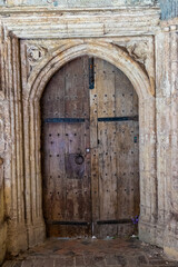 Fototapeta na wymiar Closed medieval wooden arched door with a beautifully decorated stone frame