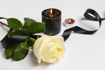Beautiful rose with candles and black ribbon on white background
