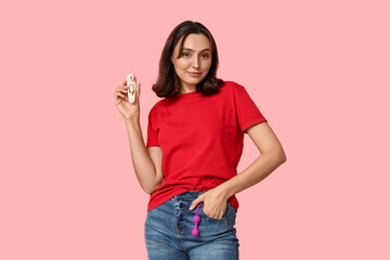 Beautiful young woman with different sex toys on pink background