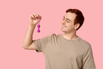 Handsome young man with anal plug on pink background