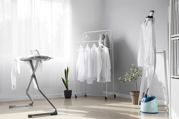 Interior of room with ironing board, steamer and white shirts - obrazy, fototapety, plakaty