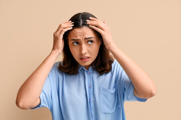 Worried young woman with dandruff on beige background, closeup