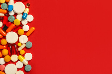Heap of different pills on red background