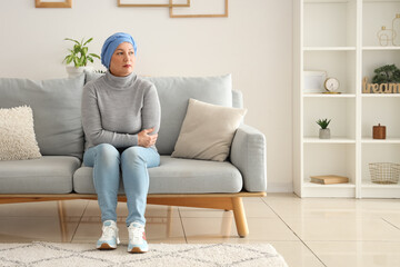 Mature woman after chemotherapy sitting on sofa at home. Stomach cancer concept