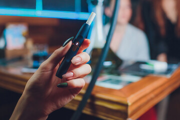 heat-not-burn tobacco product technology. woman holding e-cigarette in his hand before smoking.