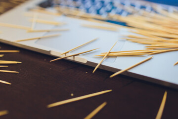 many wooden toothpicks on the brown table background a laptop.
