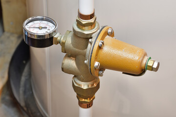 House main water feed pipe. Water line pressure regulator and pressure gauge mounted on PEX white tubes. City water entry point into a building. Water pressure control device. - obrazy, fototapety, plakaty