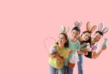 Happy family in bunny ears with Easter gifts on pink background