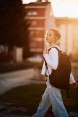A beautiful European teenager, captured in a side-profile portrait, walks home during sunset after...