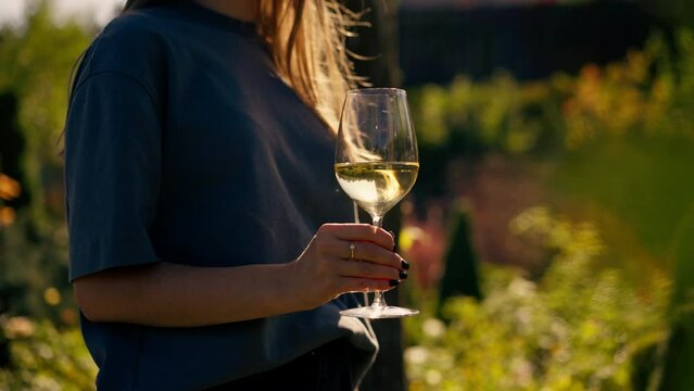 Close Up Of A Woman Holding A Glass Of White Wine Outdoors In A Garden In The Sun Tasting At A Winery