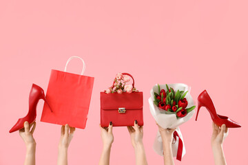Female hands with bouquet of tulips, high heel shoes and handbag on pink background. Shopping for...