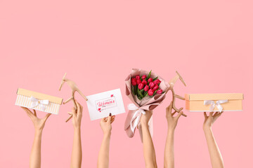 Female hands with bouquet of tulips, high heel shoes and gift boxes on pink background. Shopping...