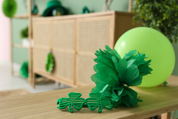Clover shaped novelty glasses and decorations for St. Patrick's Day celebration on wooden table, closeup