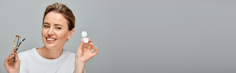 jolly attractive woman with blonde hair and glasses holding contact lenses and looking away, banner