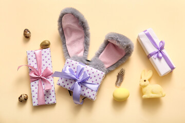 Bunny ears with Easter eggs and gift boxes on beige background