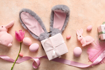 Bunny ears with Easter eggs, gift boxes and tulip flower on beige grunge background