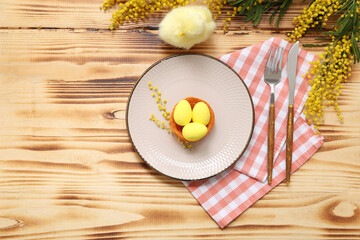 Beautiful Easter table setting with Easter eggs, chick and mimosa on wooden background