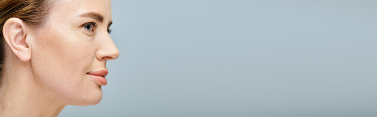 attractive blonde woman in casual attire with collected hair looking away on gray backdrop, banner