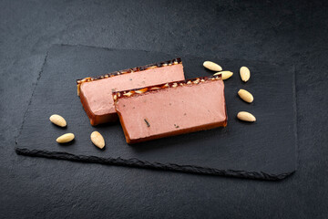 Traditional French veal liver pate with almonds and mushrooms offered as close-up on a black tray...