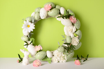 Small bunny, Easter wreath decorated with flowers and eggs on green background © Pixel-Shot