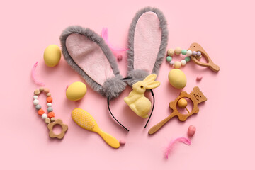 Bunny ears with Easter eggs and baby toys on pink background