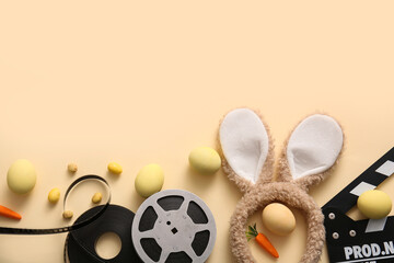 Bunny ears with Easter eggs, movie clapper and reel on beige background