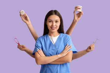 Young female dentist with hands holding dental supplies on lilac background